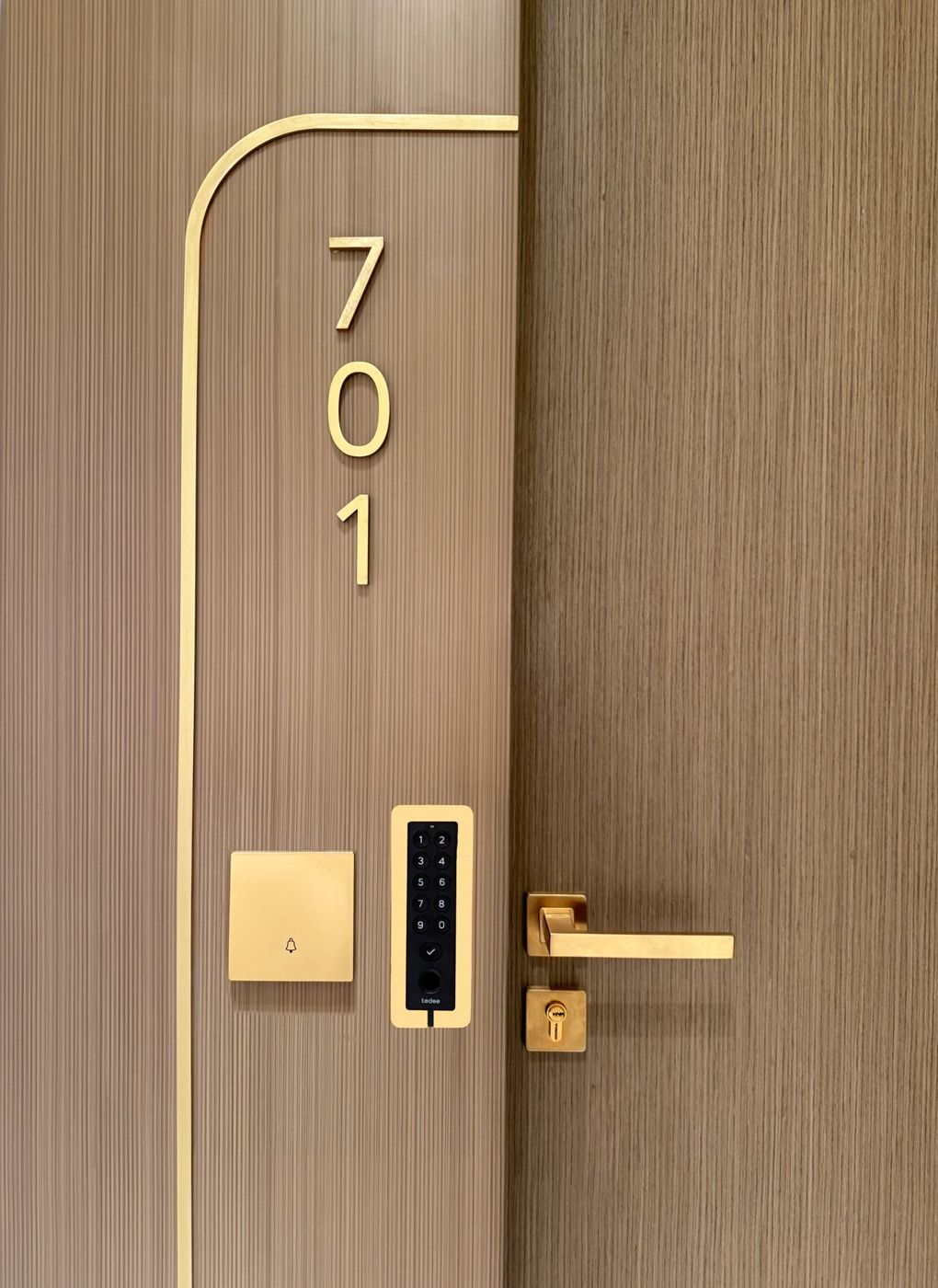 Tedee PRO smart lock in gold on a walnut door