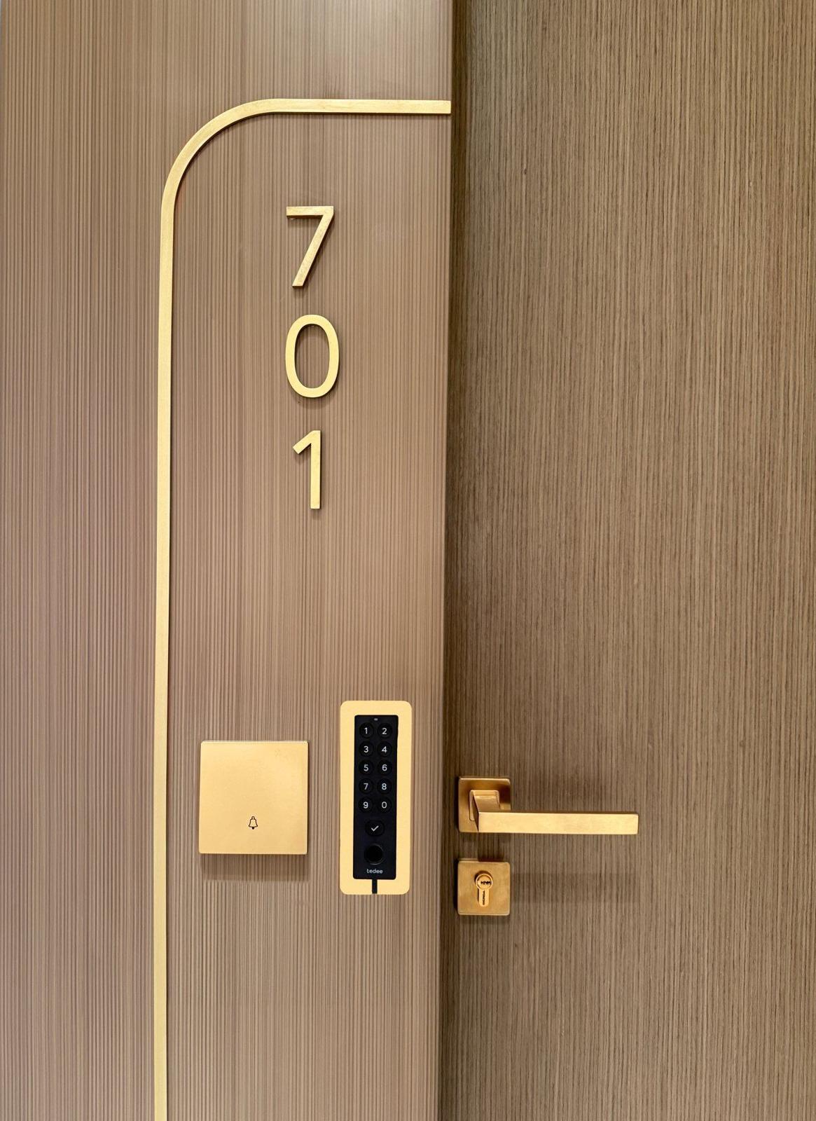 Tedee PRO smart lock in gold on a walnut door